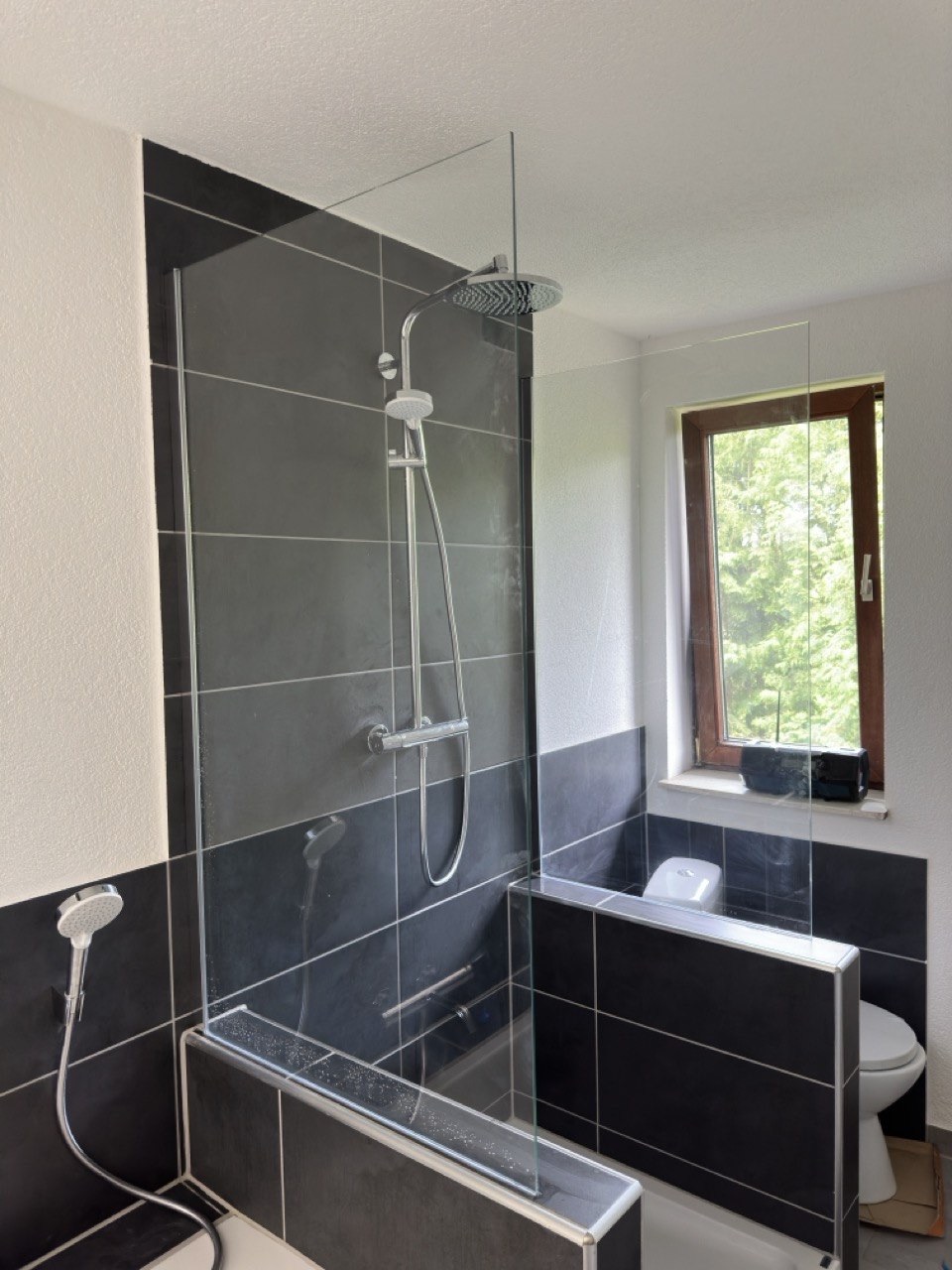 Von Sakel-Service modernisiertes Badezimmer mit ebenerdiger Dusche und anthrazitfarbenen Fliesen